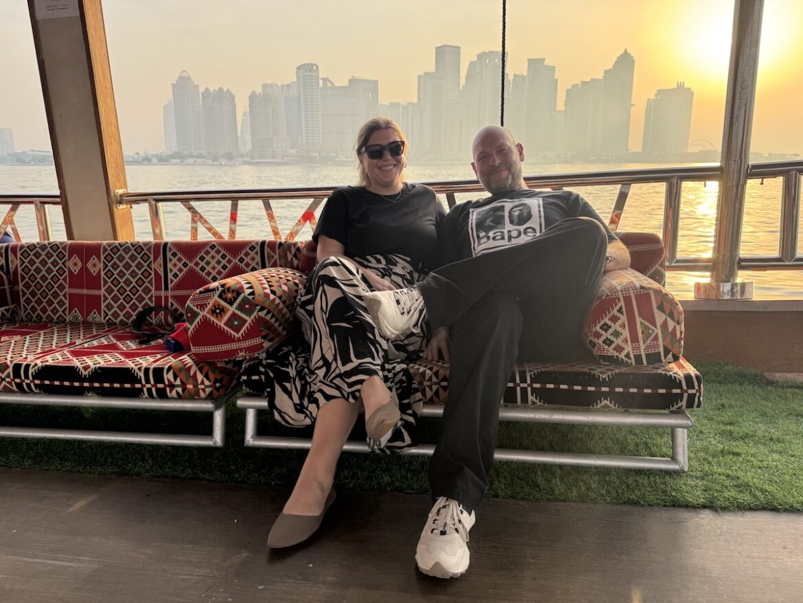 Couple on a traditional dhow boat with the Doha skyline at sunset