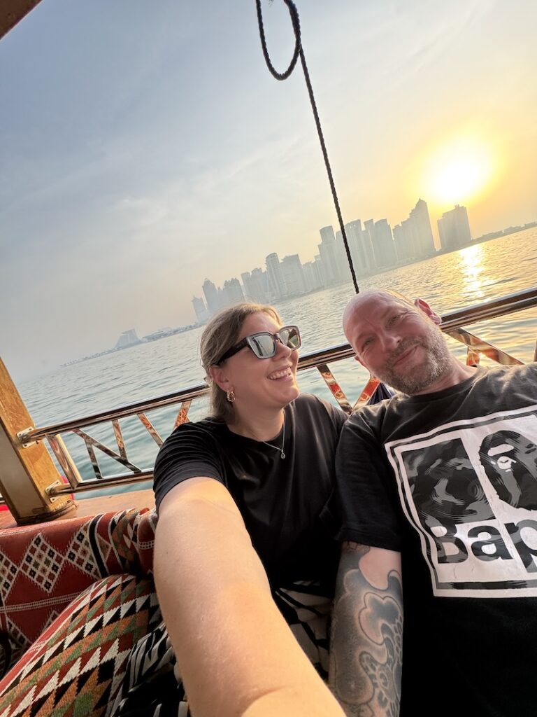 Couple on a traditional dhow boat with the Doha skyline at sunset