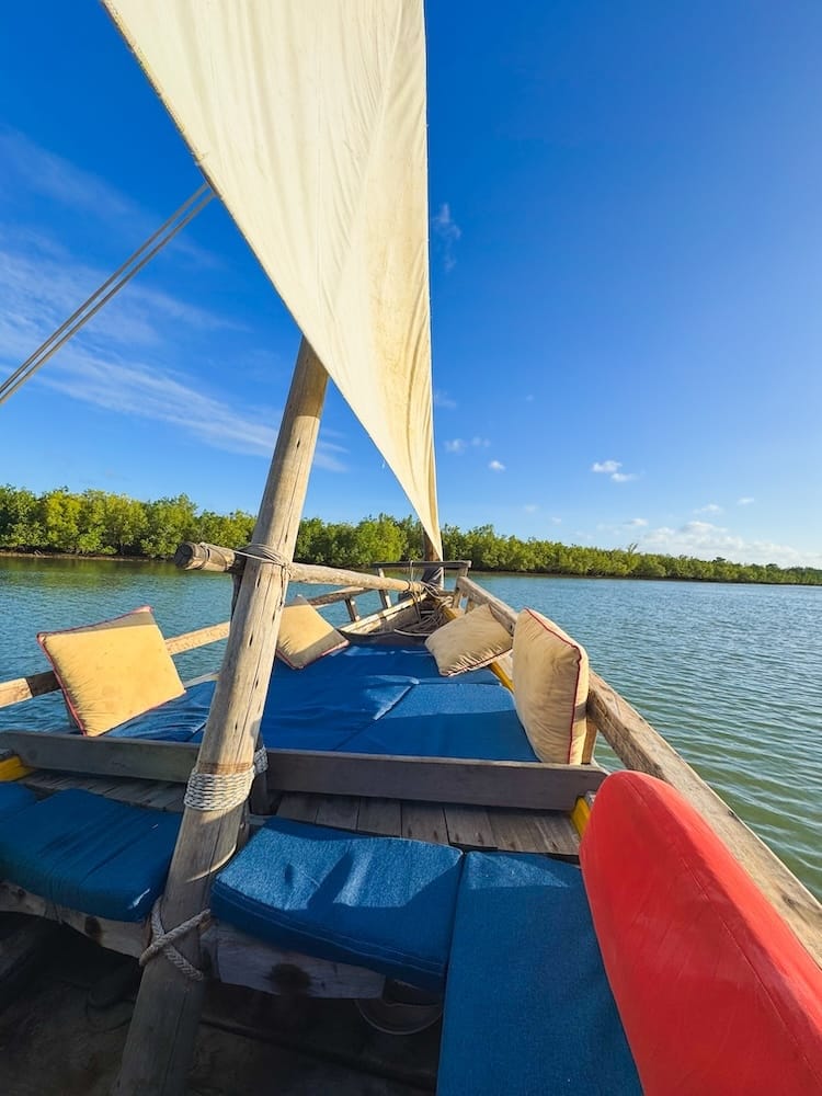 Traditional wooden dhow sailing along Kilifi Creek in Kenya at sunset.